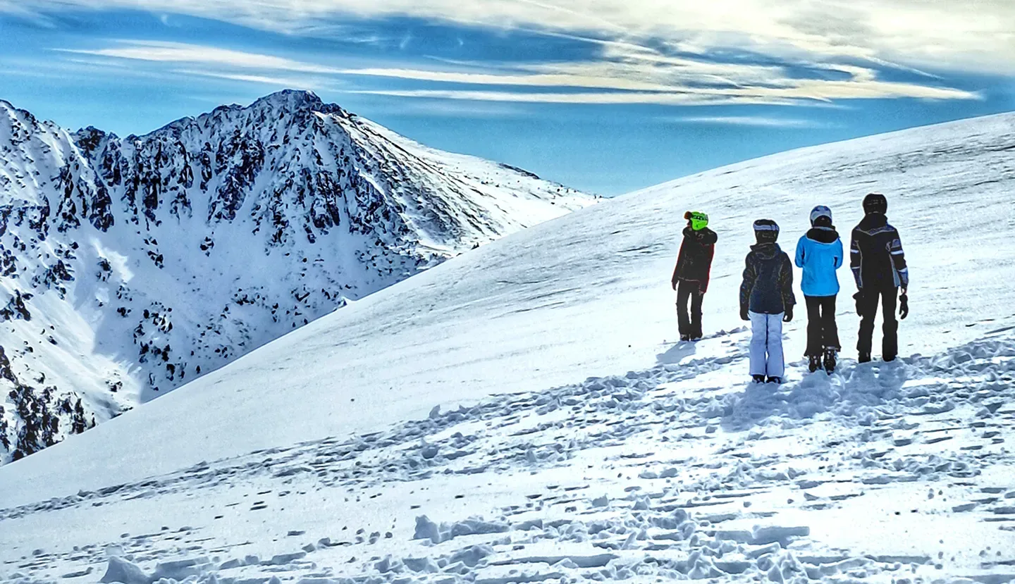 Grupo de esquiadores contemplando las montañas nevadas desde una cresta de Baqueira Beret